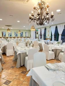 a dining room with white tables and chairs and a chandelier at Camping Las Palmeras in Crevillente