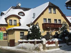 una casa con techo cubierto de nieve en Penzion Albína - Restaurace, en Vysoké nad Jizerou