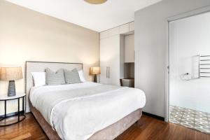 a white bedroom with a large bed and a glass door at Balmain Wharf 1 bedroom Apartments in Sydney