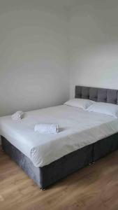 a large bed in a room with a white wall at ASM London Road Studio Apartments in Leicester