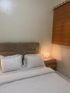ヌアクショットにあるNouakchott INNのベッドルーム1室(白い枕とランプ付きのベッド1台付)