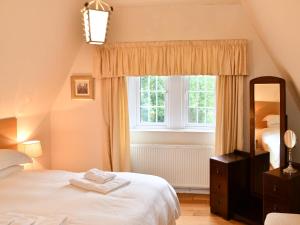 1 dormitorio con cama blanca y ventana en Cloncaird Castle Estate Cottages, en Maybole