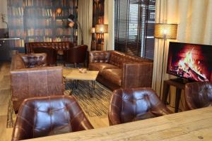 a living room with leather couches and a tv at Hôtel Du Centre Annemasse in Annemasse