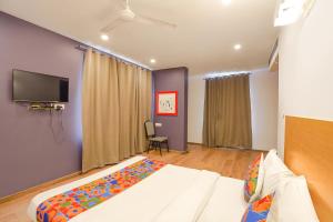 FabHotel Ramayana في Vibhuti Khand: غرفة نوم بسرير وتلفزيون بشاشة مسطحة