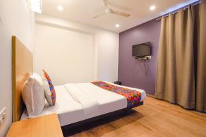 FabHotel Ramayana في Vibhuti Khand: غرفة نوم فيها سرير وتلفزيون