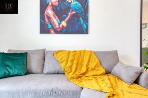 un canapé avec une couverture jaune assis sous un tableau dans l'établissement Fully equipped home, with balcony in St Julians by 360 Estates, à San Ġiljan