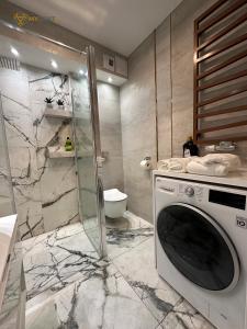 a bathroom with a shower and a washing machine at UNIA ART Apartament 61 - BASEN, SPA in Lublin