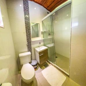 uma casa de banho com um WC e uma cabina de duche em vidro. em Pousada dos Atobás em Arraial do Cabo