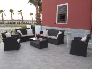 un patio con divani, tavoli e palme di L'Isola del Sale a Trapani