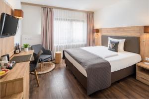 a hotel room with a bed and a desk and a tv at Neo Hotel Linde Esslingen in Esslingen