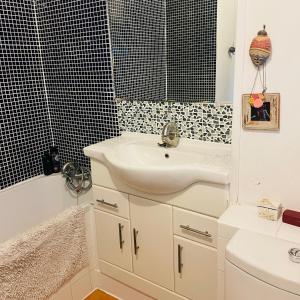 a white bathroom with a sink and a bath tub at Little Temple in Ladywell in London