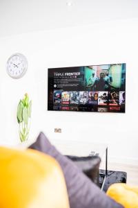 a tv hanging on a wall next to a couch at Fancy 2-Bedroom Apartment with 2 Bathrooms in Bradford Town Centre in Bradford