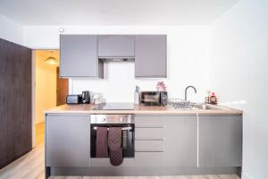 a kitchen with white cabinets and a stove at Fancy 2-Bedroom Apartment with 2 Bathrooms in Bradford Town Centre in Bradford