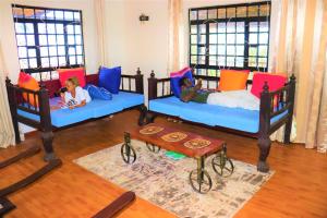 two children laying on beds in a room with windows at Saba Holiday Homes in Machakos