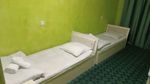 two beds in a room with green walls at DAVR хостел in Namangan