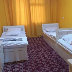 two beds sitting in a room with a carpet at DAVR хостел in Namangan