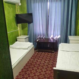 a room with two beds and a desk in it at DAVR хостел in Namangan