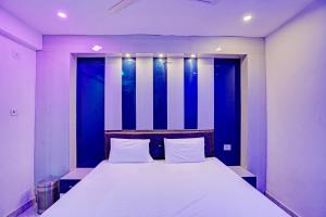 a bedroom with a large white bed with a blue wall at OYO Moon Sez in Auraiya