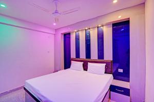 a bedroom with a bed with white sheets and a window at OYO Moon Sez in Auraiya