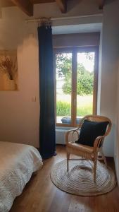 ein Schlafzimmer mit einem Stuhl vor einem Fenster in der Unterkunft Gîte de charme en pleine nature in Saint-Jean-la-Poterie