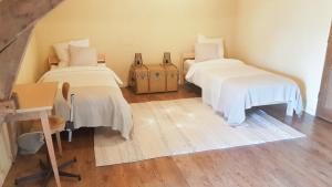 Zimmer mit 2 Betten, weißer Bettwäsche und einem Schreibtisch in der Unterkunft Gîte de charme en pleine nature in Saint-Jean-la-Poterie