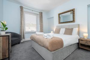 ein Schlafzimmer mit einem Bett, einem Sofa und einem Spiegel in der Unterkunft St James Place 4 bed Apt with JOIVY in Plymouth
