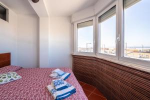 a bedroom with two beds and two windows at Akisol Caparica Alive in Costa da Caparica