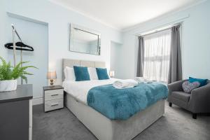 ein Schlafzimmer mit einem Bett, einem Stuhl und einem Spiegel in der Unterkunft St James Place 4 bed Apt with JOIVY in Plymouth