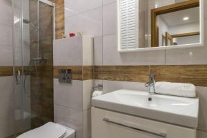 VacationClub - Spokojna 24A Apartament D1 في فيسلا: حمام مع حوض ومرحاض ومرآة