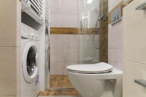 uma casa de banho com um WC e uma máquina de lavar roupa em VacationClub - Spokojna 24A Apartament D1 em Wisla