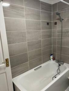 a bathroom with a white tub and a tile wall at Spacious 5 Bedroom House- Harry potter world & London in Watford