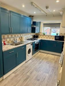 a kitchen with blue cabinets and a washing machine at Spacious 5 Bedroom House- Harry potter world & London in Watford