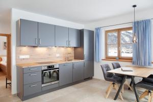 a kitchen with blue cabinets and a table and a dining room at Ferienwohnung Alpenveilchen in Grainau