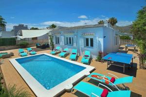 a swimming pool with chairs and a house at Villa Blau in Alcudia