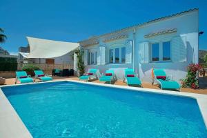 a swimming pool with chairs and a house at Villa Blau in Alcudia