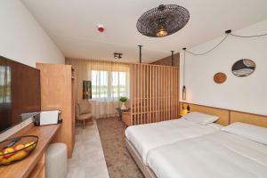 a bedroom with two beds and a desk with a television at Parc Maasresidence Thorn Lake View Hotel Rooms in Thorn