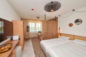 Parc Maasresidence Thorn Lake View Hotel Rooms في تورْن: غرفة نوم بسريرين ومكتب فيه تلفزيون