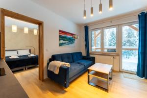 - un salon avec un canapé bleu et un lit dans l'établissement Apartament Reglowy Raj - z prywatnym parkingiem by SpaceApart, à Szklarska Poręba