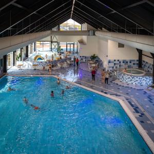 a swimming pool with people in the water at Parc Maasresidence Thorn Lake View Hotel Rooms in Thorn