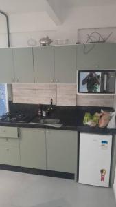 une cuisine avec des placards blancs et une personne prenant une photo dans l'établissement Lindo apartamento, Mar grosso, à Laguna