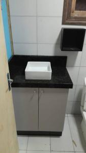 - un lavabo blanc sur un comptoir noir dans la salle de bains dans l'établissement Lindo apartamento, Mar grosso, à Laguna