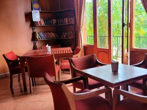 restauracja ze stołami i krzesłami oraz półką na książki w obiekcie Babylon Lodge w mieście Marangu