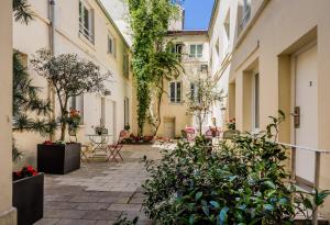 a courtyard in a building with plants and tables and chairs at The Originals City, H&ocirc;tel Lecourbe, Paris Tour Eiffel (Inter-Hotel) in Paris