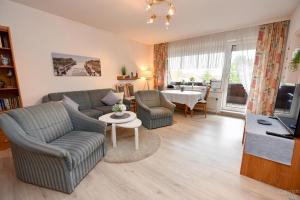 ein Wohnzimmer mit einem Sofa, Stühlen und einem Tisch in der Unterkunft Haus "Luv und Lee" Appartement LUV31 in Cuxhaven