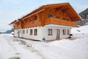 a house with a wooden roof in the snow at Ferienwohnung Gletschernelke in Grainau