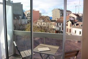 a table and a chair on a balcony with a view at Hôtel Du Centre Annemasse in Annemasse
