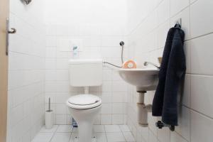 La salle de bains blanche est pourvue de toilettes et d'un lavabo. dans l'établissement Big family apartment, à Prague