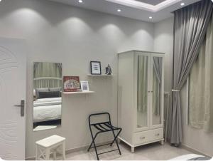 Habitación blanca con silla y dormitorio en Al Aseel Apartment Buyoot Al Diyafah, en Taif