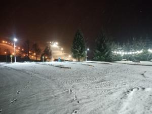 uma rua coberta de neve à noite com pegadas na neve em Tatrzański Camper Park- parcele kamperowe em Bukowina Tatrzańska