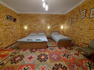 a room with two beds and a brick wall at MUSAVVIR in Samarkand